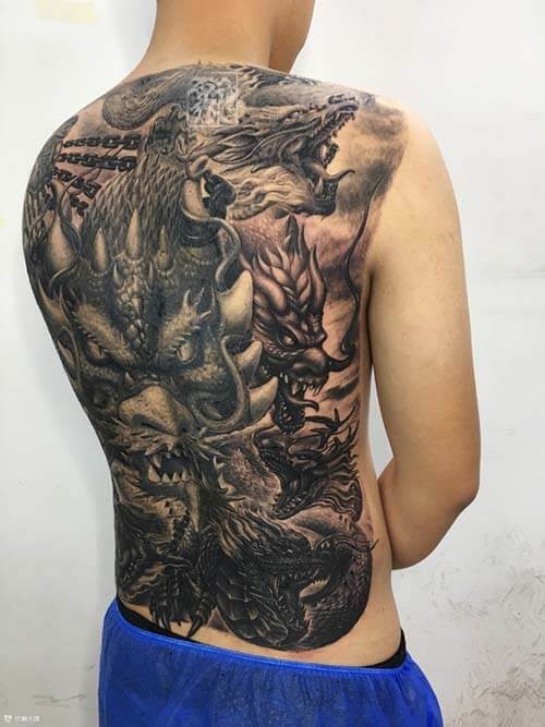 Nghệ sĩ tattoo đang thực hiện hình xăm rồng phức tạp trên lưng khách hàng