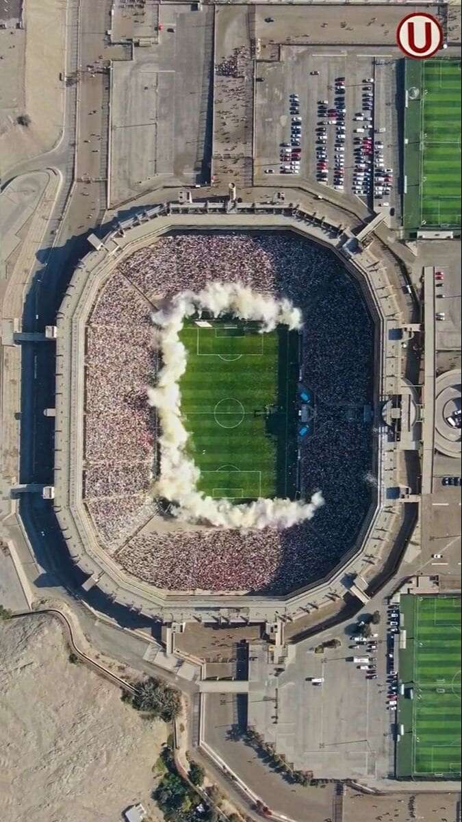 Khung cảnh sân bóng đá xanh mướt với hàng ghế khán đài trống trải, tạo cảm giác tĩnh lặng trước giờ khai cuộc