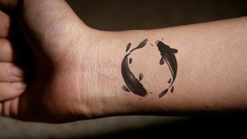 Hình xăm cá chép may mắn mini ở cổ tay, nét đen đơn giản, biểu tượng kiên định