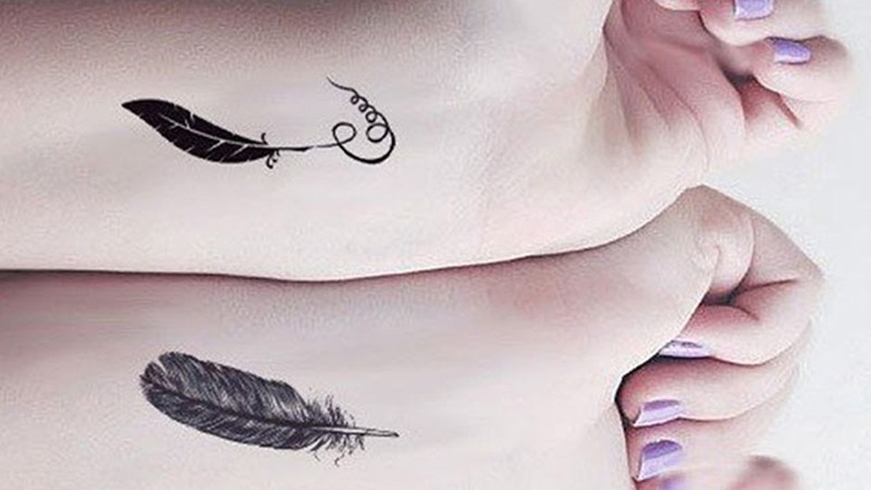 Hình xăm lông vũ đen tối giản ở cổ tay, linework tinh tế, tượng trưng tự do