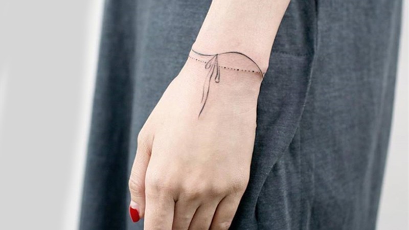 Hình xăm vòng tay tối giản dạng dây ở cổ tay, linework mảnh, hợp phong cách minimal